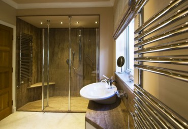 Wetroom style bathroom with shower, sink and seat.