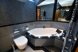 Luxury bathroom design. Silver high gloss sparkle panels surrounding white diamond bath